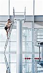 Man climbing up to a highboard in a indoor swimming pool