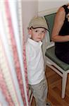 Little Boy with a Cap standing next to a Curtain - Childhood - Look