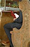 Homme assis dans le premier banc d'une église en tournant les pages d'une recueil de chansons - christianisme - fête - mariage