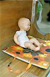 Babydoll on a Pillow with a flowery Pattern on a Bench in a Church - Toy