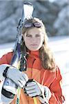 A young brown haired Woman carrying her Ski Gear and smiling towards the Camera -Wintersports - Mountain - Vacation