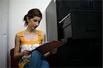 Woman reading document, sitting next to filing cabinet