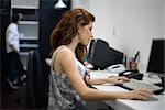 Woman working at desk, colleague standing in background