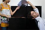 Man leaning back in chair, handing document to woman