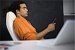 Man sitting in chair, looking down at cell phone