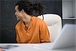 Man sitting at desk, smiling over shoulder