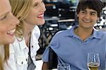 Three young friends sitting at a sidewalk cafe