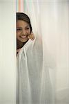 Woman peeking out curtain, smiling