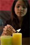 Young woman lighting candles, focus on foreground