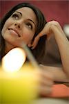 Young woman writing, holding head and looking up, candle in foreground