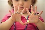 Little girl wearing several plastic rings on fingers, close-up