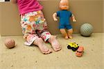 Little girl kneeling on floor with toys, rear view, cropped