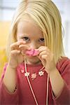 Little girl holding pink clay in front of face, portrait