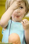Toddler girl eating with plastic spoon, close-up