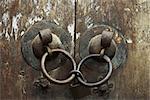 Old wooden doors, close-up of iron door handles linked by padlock