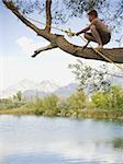 garçon sur un arbre au-dessus d'un lac.