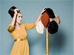 woman in 1960's attire trying on different hats