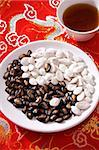 Still life of black and white melon seeds in shape of yin yang, cup of tea