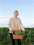 farm worker carries basket of veg