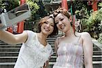 Young women at shrine with camera telephone