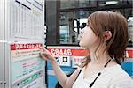 Young woman looking at bus timetable