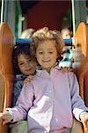 Two little girls sitting together on slide, portrait