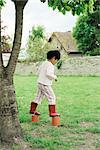 Little girl using plastic buckets as stilts, side view