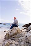 Man Sitting on Rocks on the Beach