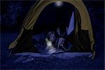 Girls in Tent at Night, Using Flashlight to Read Magazine