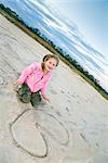 Girl and Heart Drawn in Sand at Beach