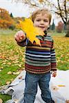 Kleiner Junge hält ein Ahornblatt im Herbst, Portland, Oregon, USA