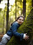 Kleines Mädchen umarmt ein Moosbedeckter Baum, Muir Woods National Monument, Kalifornien, USA