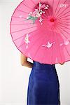 young Chinese woman in blue cheongsam holding pink umbrella