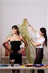 Chinese fashion designer draping cloth over model, taking measurements