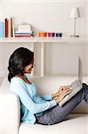 woman sitting on couch, using laptop