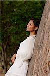 woman leaning on tree, looking away