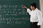 teacher explaining formula at chalkboard