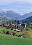 Saanen village church in foreground, fashionable resort of Gstaad in background, Swiss Alps, Switzerland, Europe