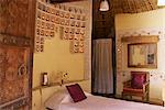 Raised mud reliefs inlaid with mirror on the walls in bedroom of modern home in traditional tribal Rabari round mud hut, Bunga style, near Ahmedabad, Gujarat state, India, Asia