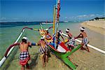 Männer starten ein Fischerboot Ausleger von Sanur Beach auf der Insel Bali in Indonesien, Südostasien, Asien