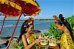Two women prepare an offering to the sea at Jimbaran Beach on the island of Bali, Indonesia, Southeast Asia, Asia