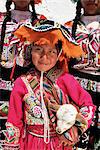 Portrait of a local smiling Peruvian girl in traditional dress, holding a young animal, Cuzco, Peru, South America