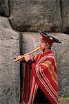 Portrait of a Peruvian man playing a flute, Inca ruins of Sacsayhuaman, Cuzco, Peru, South America
