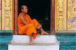 Monk sitting in temple doorway, Wat Xieng Thong, Luang Prabang, Laos