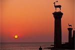 Statues de Buck à l'entrée du port de Mandraki, silhouette à l'aube, Rhodes, îles du Dodécanèse, îles grecques, Grèce, Europe