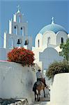 Figure on donkey passing church bell tower and dome, Vothonas, Santorini (Thira), Cyclades Islands, Greece, Europe