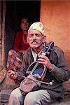 Portrait d'un homme de Gaines, caste de musiciens jouant d'un instrument à cordes et en regardant la caméra, à Pokhara, Népal, Asie