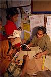 A Bangladeshi woman teacher marks students books in a school in the slums of Dhaka (Dacca), Bangladesh, Asia
