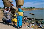 Women with baskets of laundry on their heads beside the river, Djenne, Mali, Africa