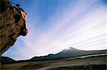 Rock climber attempts bouldering, and volcano in background, Conguillio National Park, Chile, South America